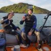 Two people sat on a boat in diving gear