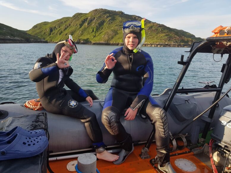 Two people sat on a boat in diving gear